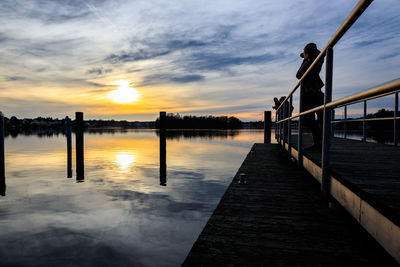 Pier over lake against sky during sunset