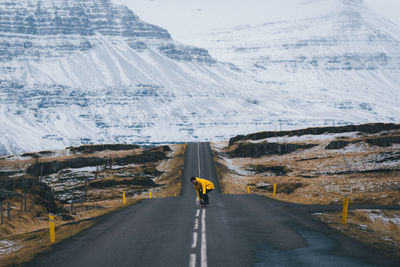 Rear view of man walking on road by mountain