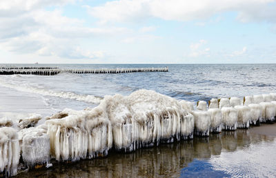 Scenic view of icicle on groyne at baltic sea against sky