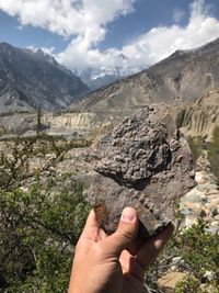 Midsection of person holding rock in mountains