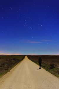 Rear view of man on road against clear blue sky