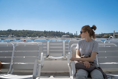 Full length of woman sitting on chair against sky