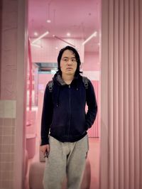 Portrait of young asian man standing against pink room and wall