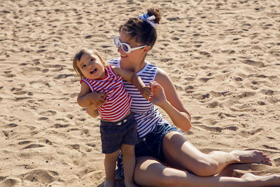 Woman walks with her little son on a sandy beach near the sea in the summer