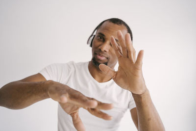 Portrait of man wearing headphones gesturing against white background