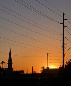 Low angle view of silhouette electricity pylon against sky during sunset