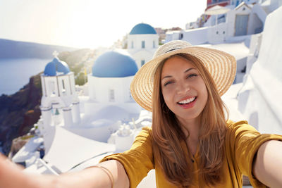 Brazilian young fashion woman taking self portrait on sunset in santorini island, greece