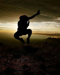 Silhouette man on field against sky at sunset