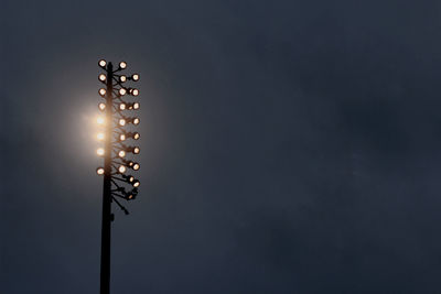 Low angle view of illuminated flood light against sky at night