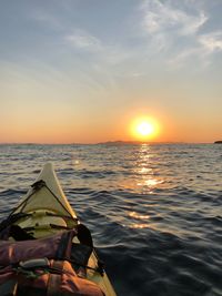 Kayak on sea against sky during sunset