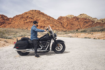 Rear view of man riding motorcycle on road