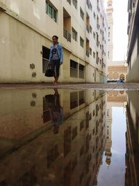 Reflection of man on water in city