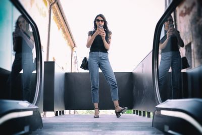 Full length of woman standing on mobile phone