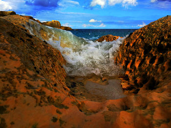 Scenic view of rocks on beach against sky