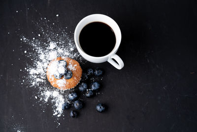 High angle view of coffee with muffin and blueberries on table