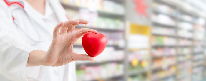 Midsection of woman holding heart shape in store