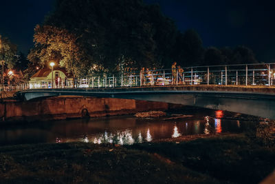 Illuminated bridge over river in city at night