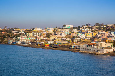 Aerial view of townscape by sea against clear sky