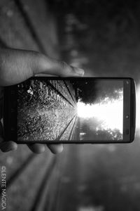 Close-up of hand holding camera against sky