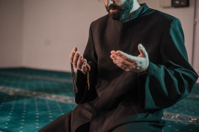 Midsection of man holding while sitting outdoors