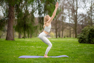 Full length of woman exercising on field