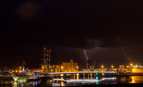 Illuminated harbor against sky at night