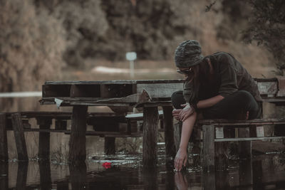 Woman sitting on bench by the lake