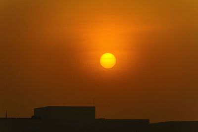 Silhouette building against orange sky