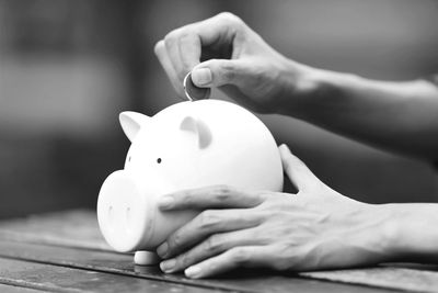Cropped hand of man inserting coin in piggy bank