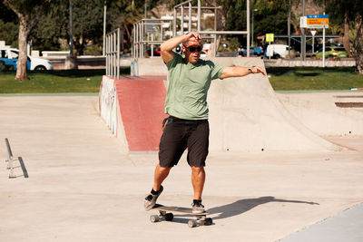 Man riding skateboard in urban street skatepark. casual guy wearing shorts and t-shirt.