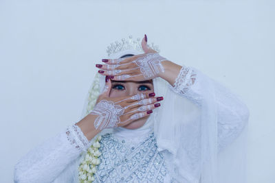 Portrait of young woman wearing mask against white background