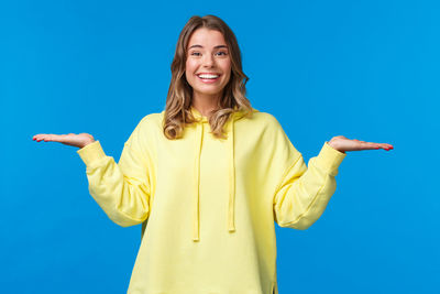 Smiling young woman standing against blue background