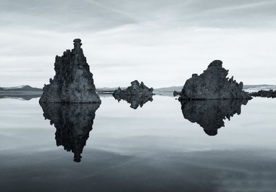 Reflection of rocks in calm lake against sky