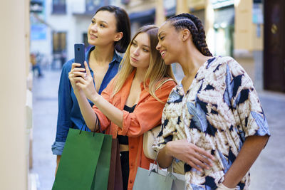 Smiling friends using mobile phone