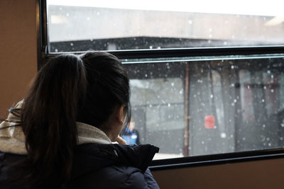 Rear view of woman on wet window