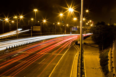 Light trails on city street against clear sky at night