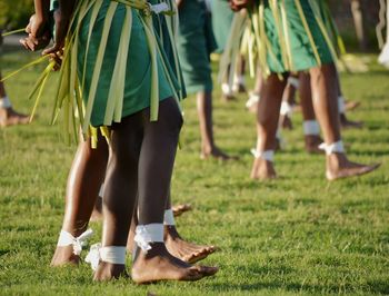 Low section of women dancing on grassy field