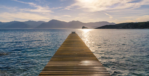 Pier over lake against sky during sunset