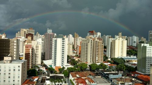 Rainbow over cityscape against sky