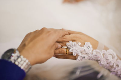 Cropped hand of bride holding wedding dress