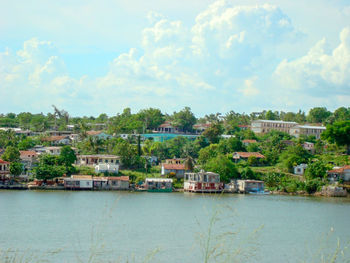 Scenic view of river by buildings against sky