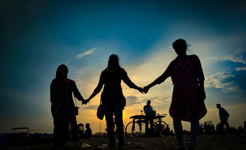 Silhouette people standing on land against sky during sunset