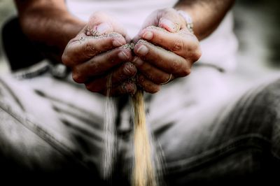 Close-up of hands releasing sand