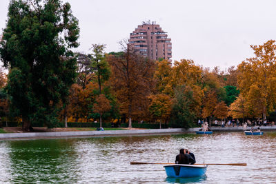 People on boat by river against trees