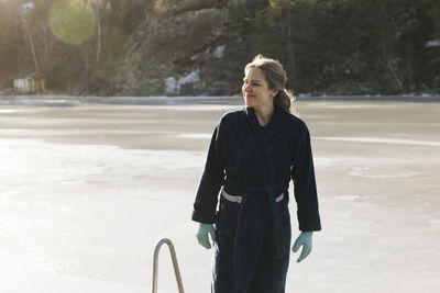 Smiling woman wearing dressing gown at water