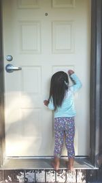 Rear view of girl knocking door