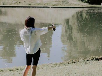 Portrait of a beautiful girl from the back makes a selfie on a smartphone while relaxing in the park 