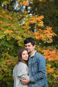 Portrait of young couple standing against plants