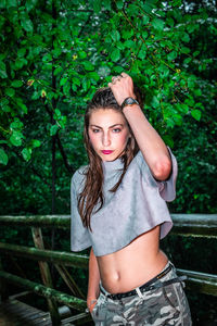 Portrait of beautiful young woman standing against plants