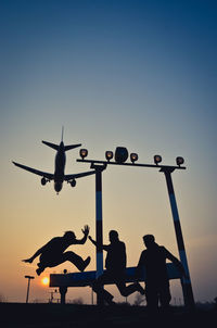 Friends enjoying with airplane flying against sky